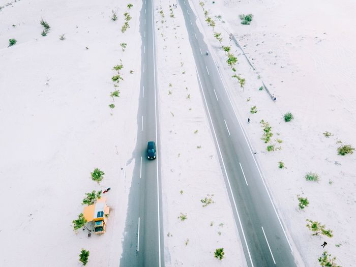 Con đường nhựa uốn lượn giữa đồi cát trắng và hồ nước xanh