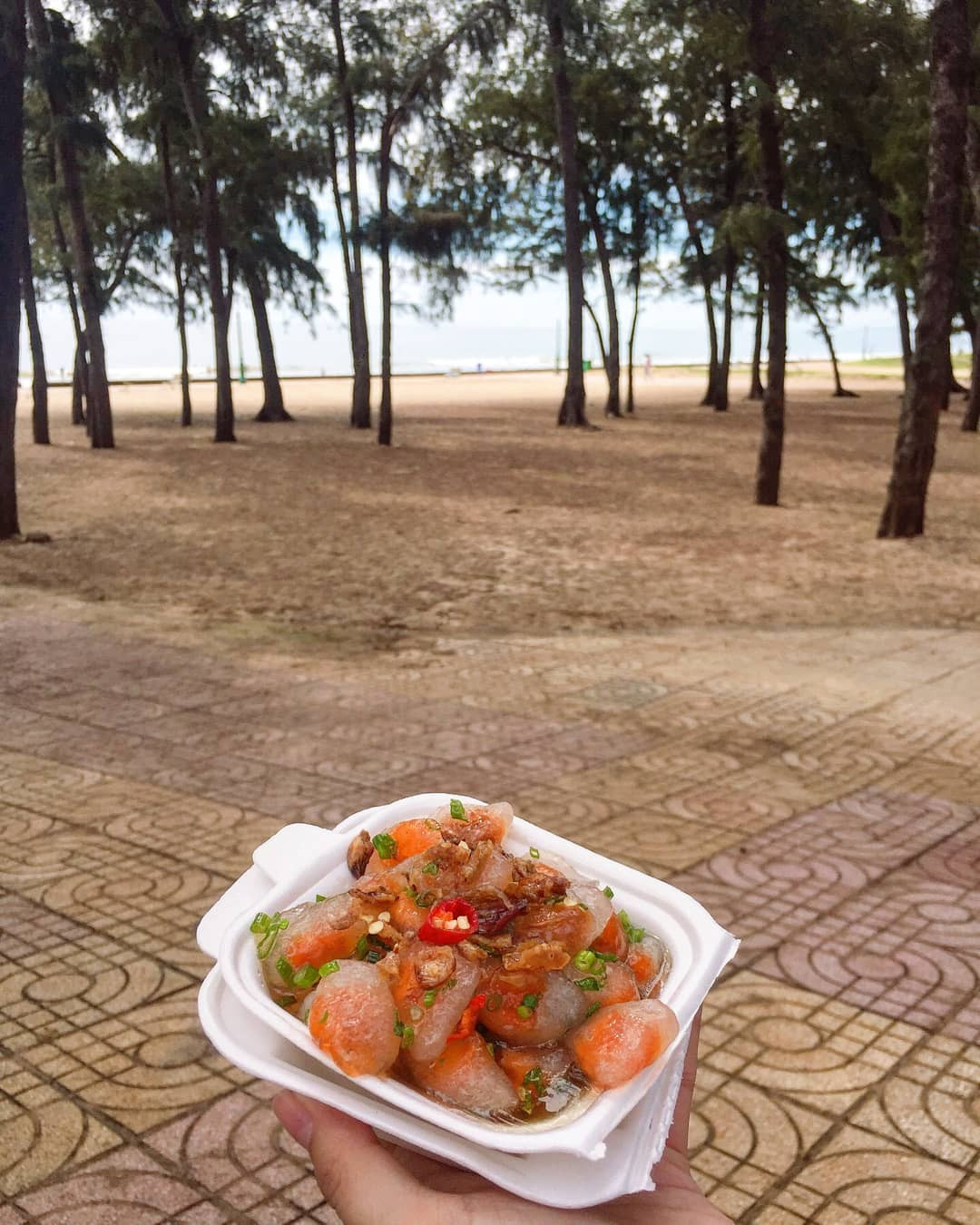 Du khách mua bánh quai vạc từ gánh hàng rong tại Biển Đồi Dương