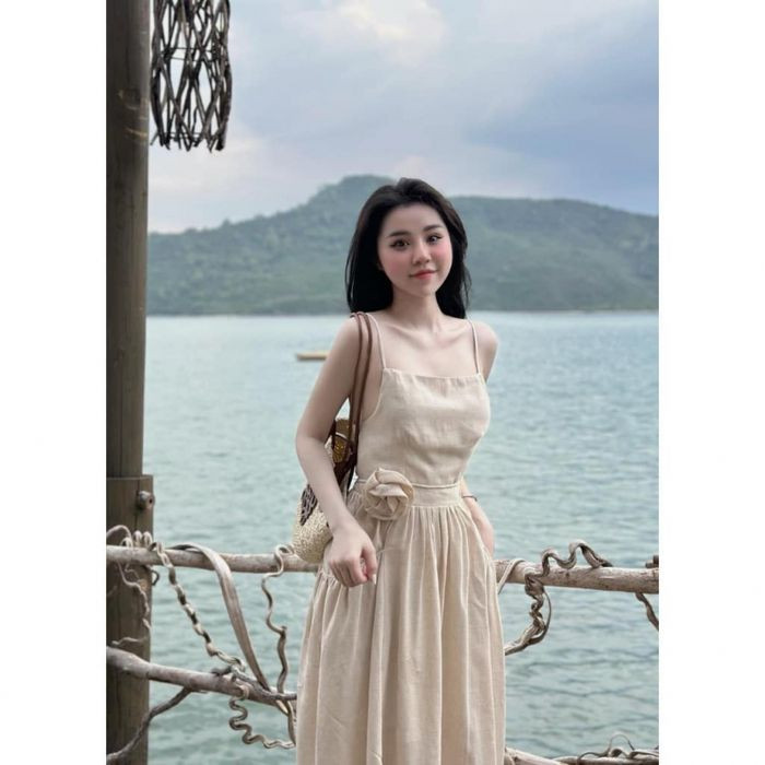 Một cô gái mặc váy maxi màu xanh dương tươi sáng, tạo dáng chụp ảnh trên bãi cát