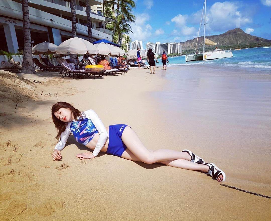 Một phụ nữ trẻ ngồi trên cát đeo sandal thể thao