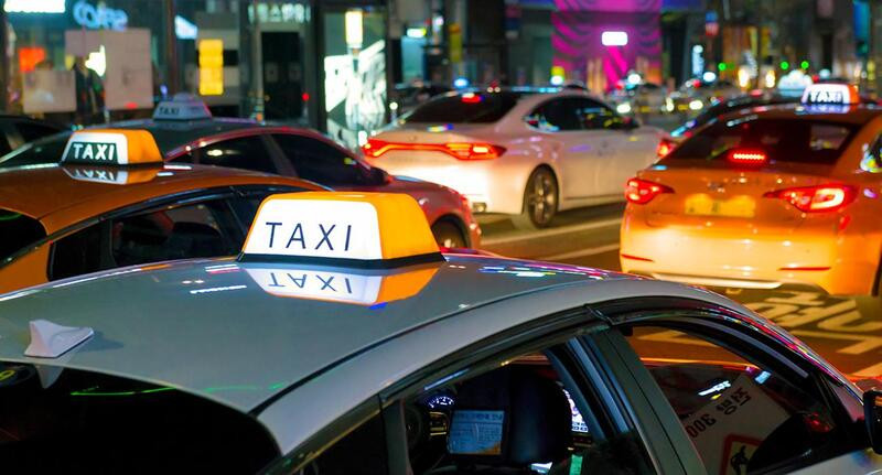 Xe taxi Đức Linh màu trắng đang di chuyển trên đường, biểu tượng cho dịch vụ nhanh chóng tại Phan Thiết
